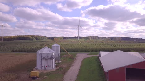 Aerial-footage-flying-over-farmland-with-red-barns-and-steel-silos-with-conveyers