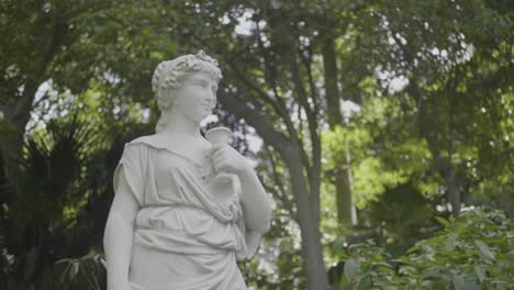 Estatua-De-Una-Mujer-Joven-Rodeada-De-árboles-En-Un-Parque.
