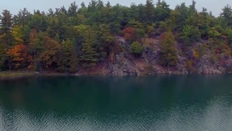 Backwards-aerial-tracking-shot-of-Pink-Lake-at-Gatineau-Park-during-Autumn