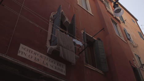 Dry-towels-hanging-in-front-of-a-window-on-a-red-building-in-Venice,-Italy