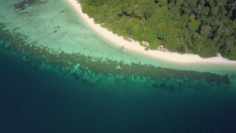 Vista-Aérea-De-La-Isla-Tailandesa-Con-Una-Increíble-Playa-De-Arena-Y-Aguas-Cristalinas-Con-Arrecifes-De-Coral