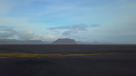 ángulo-De-Drones-De-Las-Montañas-Cerca-De-La-Playa-De-Arena-Negra-En-Islandia
