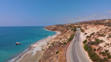 Aerial-view-flying-over-a-road-near-the-beach-and-coast-of-the-Mediterranean-Sea-in-Paphos-Cyprus