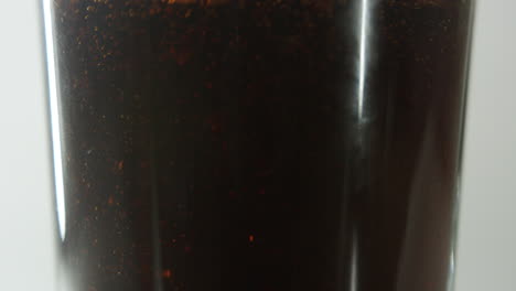 middle-section-of-a-clear-glass-shown-being-filled-with-cola-drink-against-clear-light-background