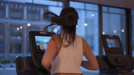 Young-Woman-Working-out-Cardio-on-treadmill-at-Gym-During-Night-with-Large-Windows-In-Front-of-Her-with-camera-movement-4K-ProRes