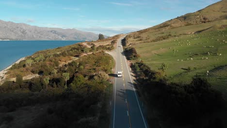 Slowmo-Luftdrohne,-Die-Einem-Wohnmobil-Folgt,-Mit-Blick-Auf-Den-Herrlichen-Blauen-Lake-Hawea,-Das-Schaffeld-Und-Die-Berge-Am-Späten-Nachmittag-In-Neuseeland