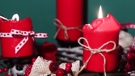 Anzünden-Von-Kerzen-Auf-Einem-Modernen-Weihnachtskranz-Mit-Vier-Roten-Kerzen-Auf-Einer-Holzoberfläche-Mit-Grünem-Hintergrund,-Festliche-Innenarchitektur,-Schwenk-Von-Rechts-Nach-Links