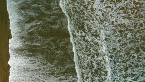 Aerial-view-of-incoming-waves-rolling-over-the-beach-at-the-90-mile-beach,-new-Zealand