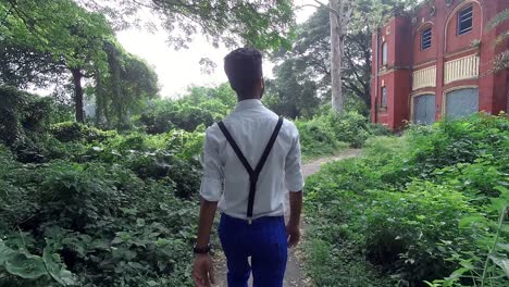 Alone-fashionable-young-male-walk-towards-scary-abandoned-house-in-forest,-slow-motion