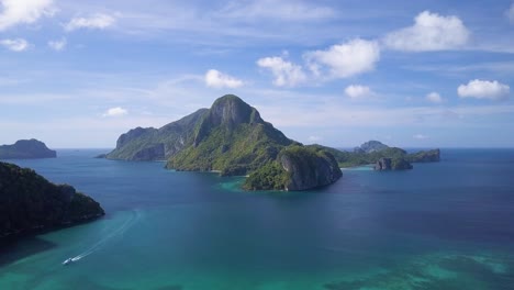 Aerial-tracking-shot-pedestal-up-of-famous-giant-limestone-cliff-in-Bacuit-Archipelago-close-to-El-Nido-town,-Palawan,-the-Philippines-on-sunny-day