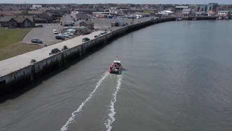 Aerial-view-of-small-fishing-boat-entering-the-harbour-at-Amble-in-Northumberland-UK