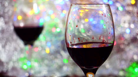 Red-Wine-glass-in-foreground-on-colorful-bokeh-and-silver-blanket-close-up-in-a-romantic-intimate-atmosphere