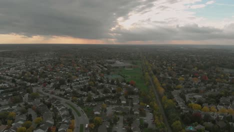 Luftaufnahmen-Von-Links-über-Einige-Bahngleise,-Die-Mitten-Durch-Zwei-Unterbezirke-Verlaufen-Und-Zu-Einem-Riesigen-Sonnenuntergang-Im-Herbst-Führen