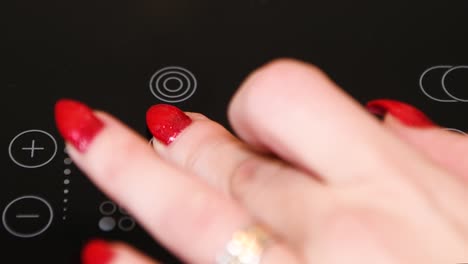 Weiblicher-Finger-Bedient-Elektroherd,-Schön-Manikürte-Fingernägel,-Roter-Lack,-Beleuchtete-LED-Anzeigen,-Extreme-Nahaufnahme