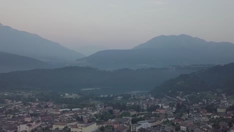 Aerial-panoramic-view-of-Levico-Terme,-Italy,-during-sunrise-with-drone-panning-right-to-left