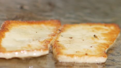 Nahaufnahme-Von-Halloumi-Käse,-Der-Auf-Einem-Grill-Brutzelt-Und-Nach-Dem-Bräunen-Mit-Einem-Spatel-Gewendet-Wird