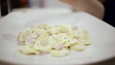 Frau-Legt-In-Zeitlupe-Geriebenen-Italienischen-Käse-Auf-Ein-Nudelgericht
