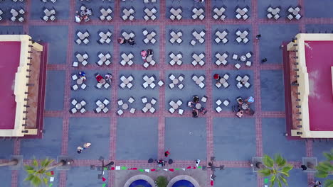 Drone-shot-looking-down-on-an-outdoor-restaurant's-table-and-chairs