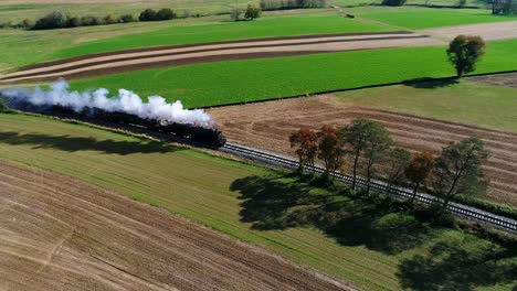Steam-Passenger-Train-Puffing-Smoke-Along-Amish-Countryside-as-Seen-by-a-Drone