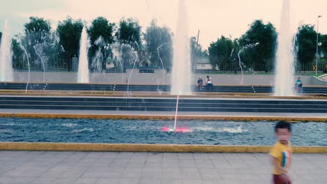 Asian-Boy-running-in-front-of-fountain-of-Laman-Serene-park-in-Johor-Bahru-in-the-evening