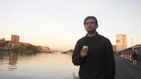 Video-of-a-man-walking-along-a-pier-in-Amsterdam-and-eating-an-apple-during-sunset