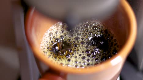 Slow-motion-of-black-coffee-drops-dripping-from-coffee-machine-into-brown-mug