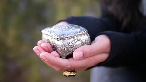 Close-up-on-a-woman-holding-a-cute-silver-vintage-jewelry-box-in-her-hands
