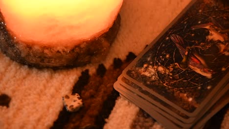 close-up-of-a-man's-hand-taking-tarot-cards-one-by-one,-near-some-stones-and-a-salt-lamp,-on-a-carpet