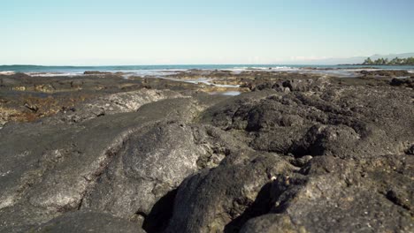 Large-curved-lava-rock-in-foreground-with-waves-hitting-the-back-of-the-formation