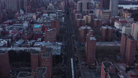 Backward-drone-flight-over-elevated-train-tracks-of-Harlem,-New-York-City-just-after-sunrise