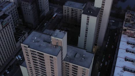 Downward-drone-flyover-highrise-rooftops-in-Harlem,-New-York-City,-just-after-sunrise,-in-4K