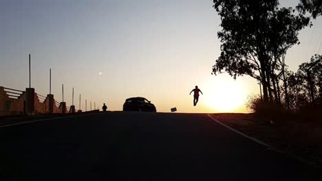 A-silhouetted-boy-running-and-jumping-up-during-sunset-in-slow-motion