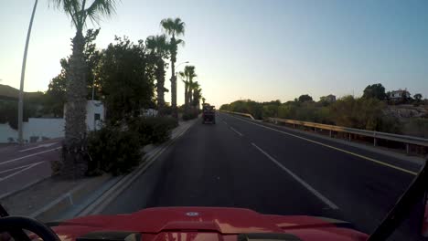 Punto-De-Vista-Conduciendo-Al-Atardecer-Por-Caminos-Bordeados-De-Palmeras-En-Chipre