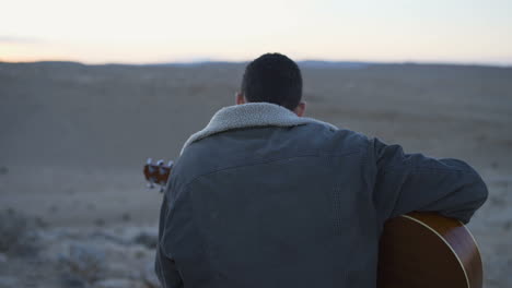 Young-man-plays-the-guitar-with-beautiful-desert-background