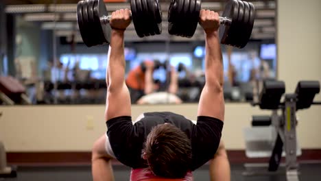 Closeup-and-head-on-shot-of-bodybuilder-doing-dumbbell-bench-presses
