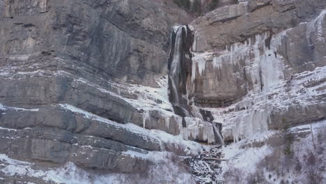 A-half-frozen-half-flowing-waterfall-flowing-down-rugged-terrain-in-the-Rocky-Mountains