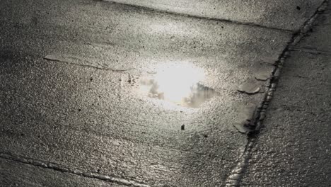 Reflection-in-puddle-shining-brightly-on-wet-asphalt-Berlin,-Germany