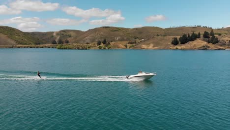 Wasserski-Hinter-Dem-Boot-Auf-Dem-Lake-Dunstan-In-Der-Nähe-Von-Clyde-Dam,-Central-Otago,-Neuseeland-Mit-Bergen-Und-Wolken-Im-Hintergrund