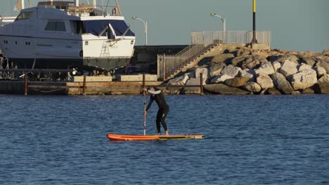 Man-paddling-in-Bormes-les-Mimosas-harbour-entrance,-Mediterranean-sea---South-of-France