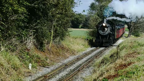 Steam-Passenger-Train-Puffing-Along-Amish-Farm-lands-and-Countryside