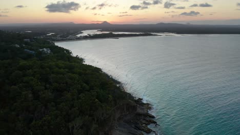 Drone-footage-filmed-in-Noosa-of-a-forest-overlooking-a-pristine-beach-with-clear-blue-green-water