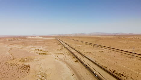 Aerial-view-of-a-long-straight-highway-stretching-through-a-barren-dessert-on-a-sunny-day