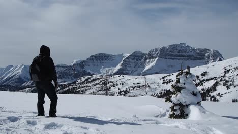 Man-walking-in-snow-on-top-of-mountain