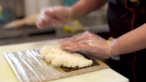 Ein-Koch-Legt-Eine-Große-Kugel-Sushi-Reis-Auf-Nori-Und-Versucht,-Sie-Zu-Pressen-Und-In-Eine-Rechteckige-Nori-Form-Zu-Formen
