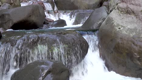 Kleine-Wasserfälle-Aus-Klarem,-Fließendem-Bergwasser,-Das-über-Große-Felsbrocken-Und-Felsen-Mit-Moos-Aus-Nächster-Nähe-Fließt