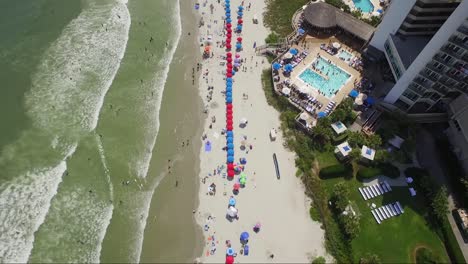 Static-bird's-eye-view-of-people-on-beach-sunbathing-under-umbrellas