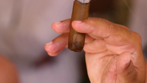 Close-up-of-Caribbean-male-wearing-sunglasses-holding-and-smoking-a-brown-cigar