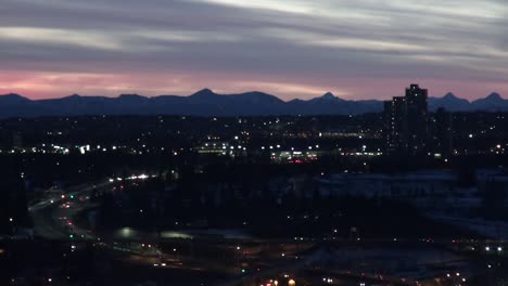 Cityscape-at-dusk-with-mountains-on-horizon