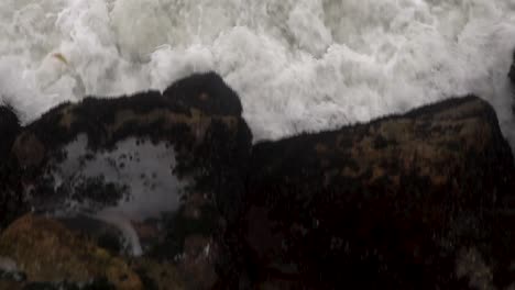 Camera-angles-down-following-specific-wave-until-it-violently-crashes-against-rocks