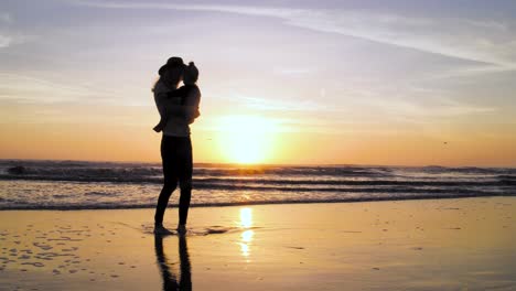 A-woman-enjoys-a-stunning-and-colorful-sunset-with-her-child-at-the-beach-in-4k